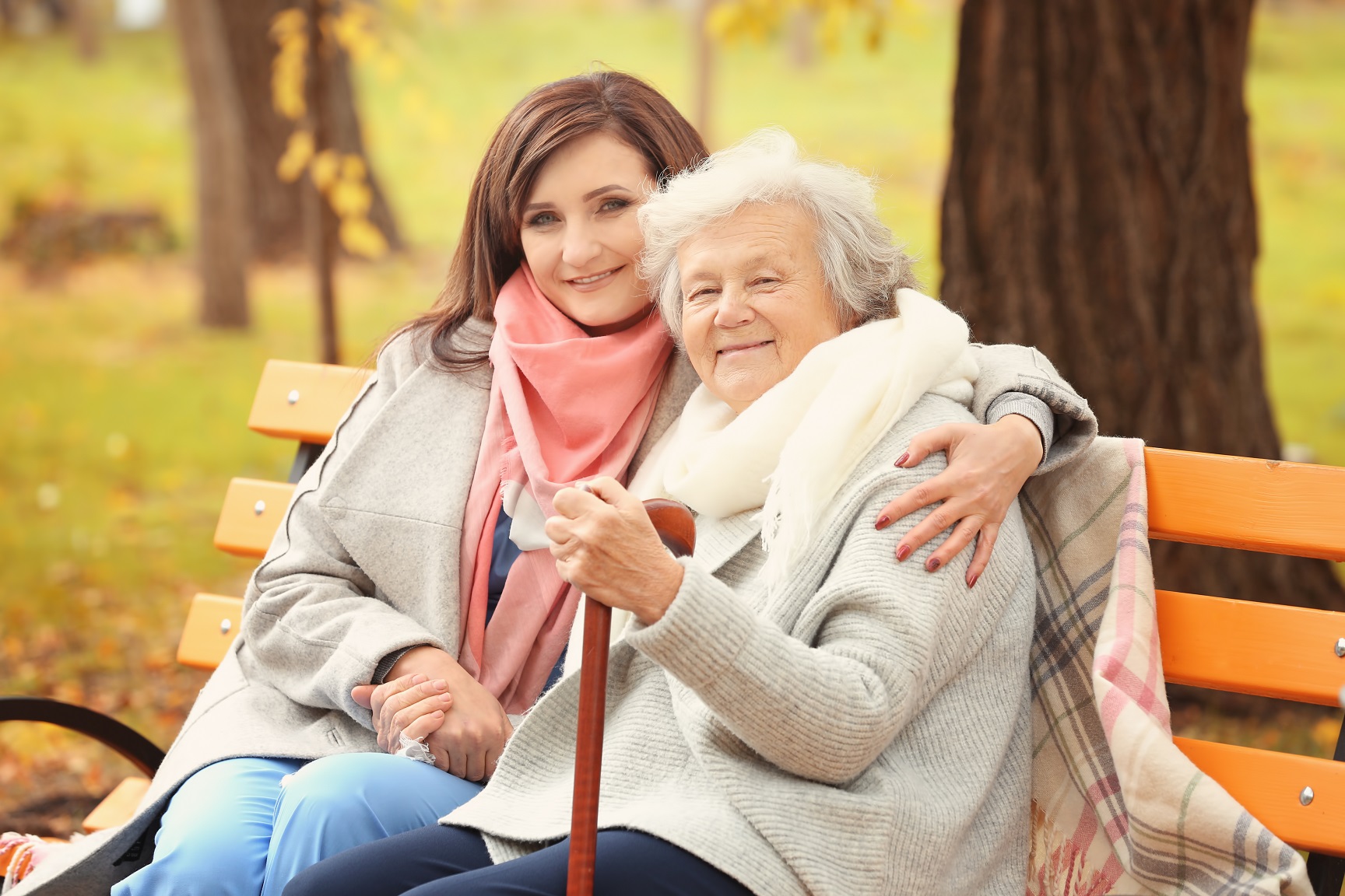 Daughter sitting with her elderly mother on a park bench.